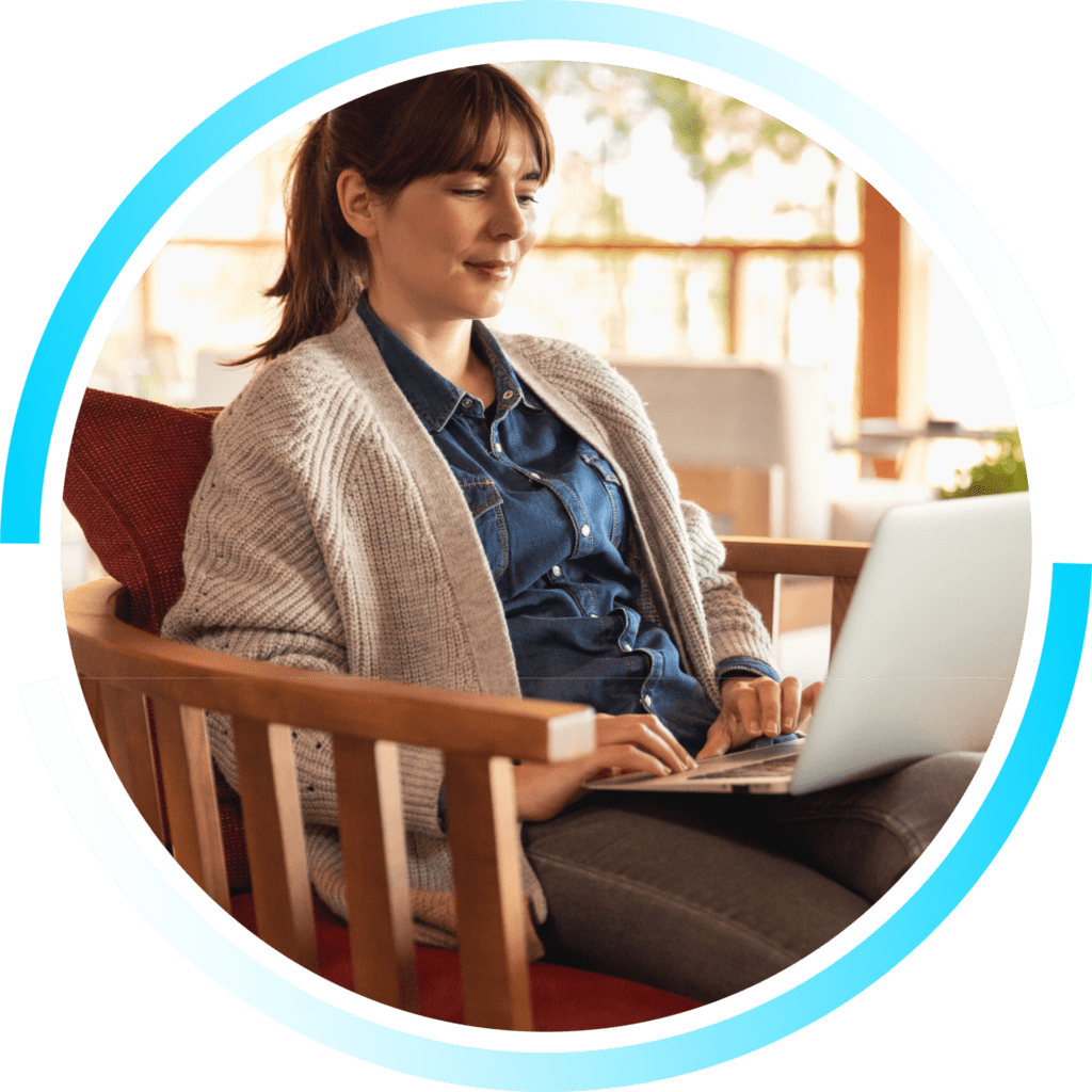 A circular image of a young woman working from home on a laptop