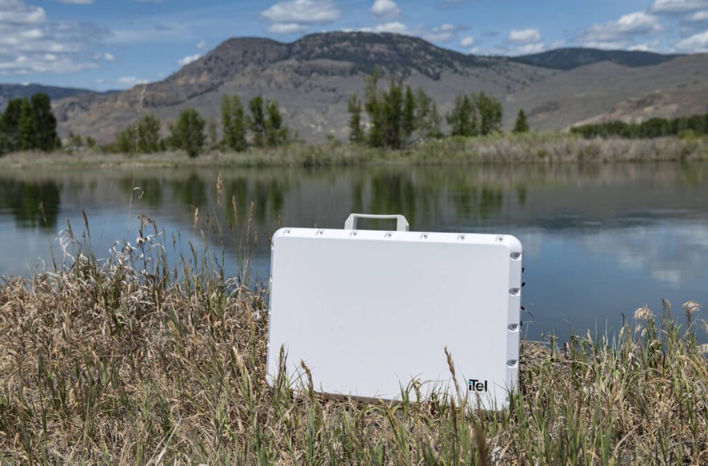 iTel iLink portable connectivity unit placed in a remote field location with mountain background