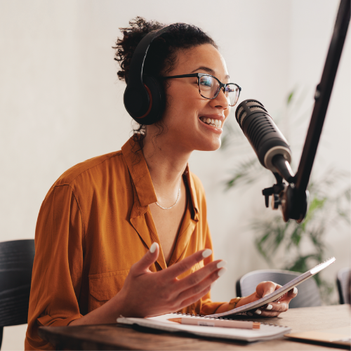 Broadcaster recording audio with microphone and headset.