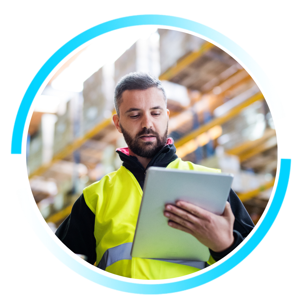 Transportation worker wearing a high-visibility vest uses a digital tablet inside a warehouse, representing real-time coordination and connected logistics operations.